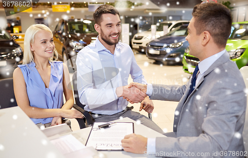 Image of happy couple with car dealer in auto show or salon