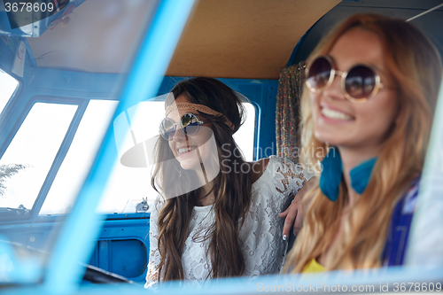 Image of smiling young hippie women driving minivan car