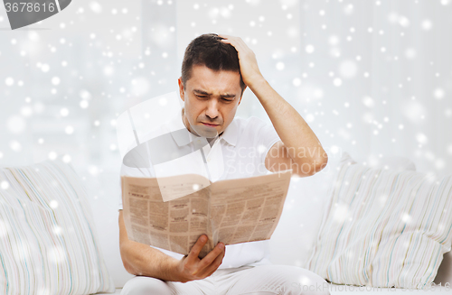 Image of sad man reading newspaper at home