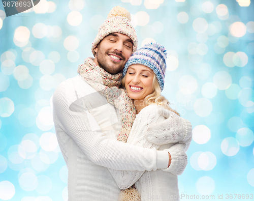 Image of happy couple in winter clothes hugging over lights