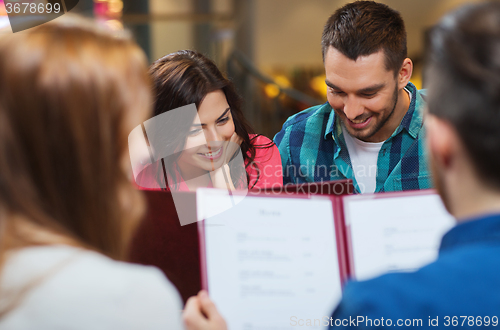 Image of smiling couple with friends and menu at restaurant