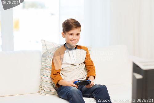 Image of happy boy with joystick playing video game at home