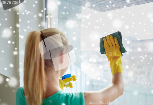 Image of happy woman in gloves cleaning window with rag