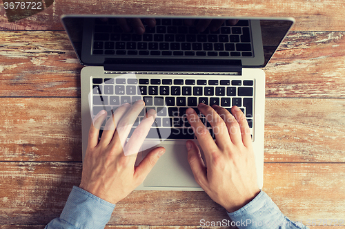 Image of close up of male hands with laptop typing