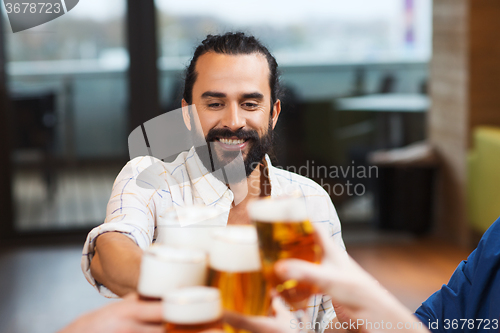 Image of man clinking beer glass with friends at restaurant