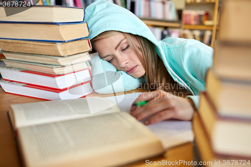 Image of student or woman with books sleeping in library