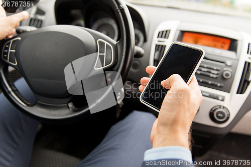 Image of close up of man hand with smartphone driving car