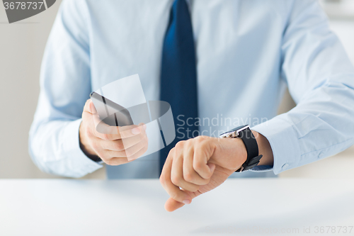 Image of close up of hands with smart phone and watch