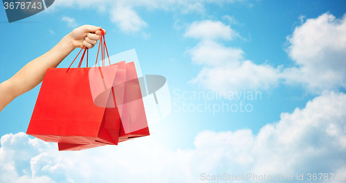 Image of close up of hand holding red shopping bags