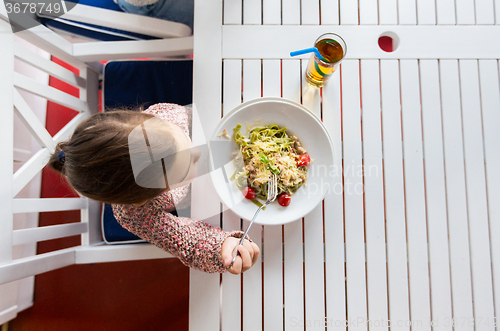 Image of little girl eating pasta for dinner at restaurant