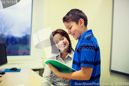 Image of school boy with notebook and teacher in classroom