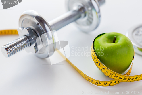 Image of close up of dumbbell and apple with measuring tape