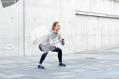 Image of happy woman doing squats and exercising outdoors