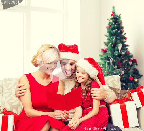 Image of happy family in santa helper hats with gift boxes