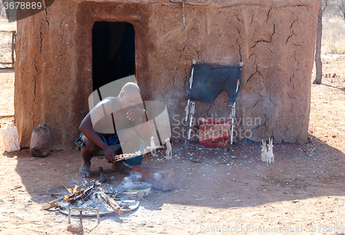 Image of Himba man adjusts wooden souvenirs