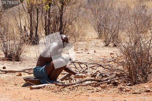 Image of Himba man adjusts wooden souvenirs