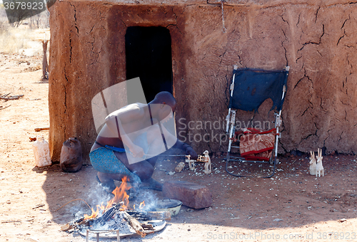 Image of Himba man adjusts wooden souvenirs