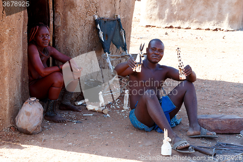 Image of Himba man adjusts wooden souvenirs