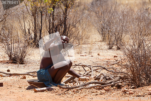 Image of Himba man adjusts wooden souvenirs