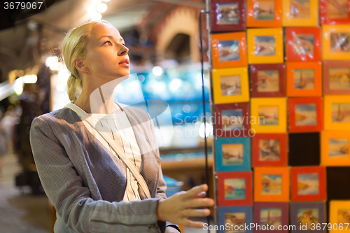 Image of Casual blond woman shopping for vacation souvenirs.