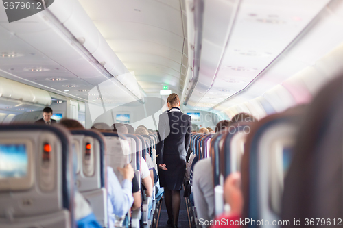 Image of Stewardess and passengers on commercial airplane.