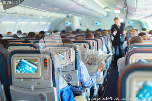 Image of Steward and passengers on commercial airplane.