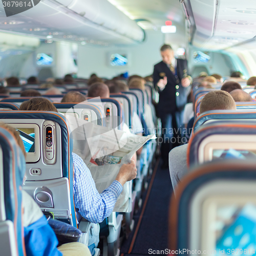 Image of Steward and passengers on commercial airplane.