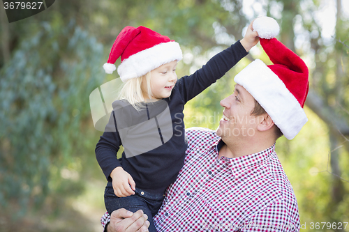 Image of Father and Daughter Having Fun Wearing Santa Hats