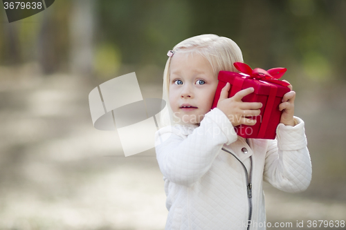 Image of Baby Girl Holding Red Christmas Gift Outdoors