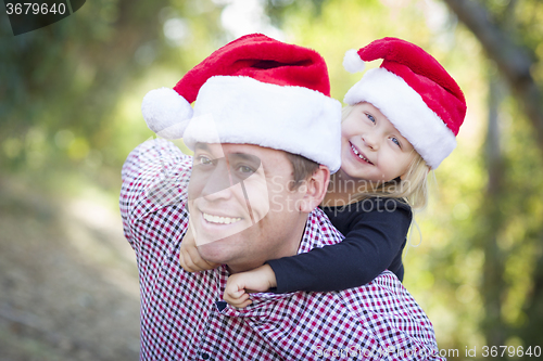 Image of Father and Daughter Having Fun Wearing Santa Hats