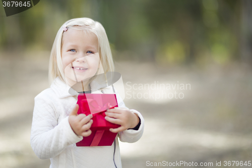 Image of Baby Girl Holding Red Christmas Gift Outdoors