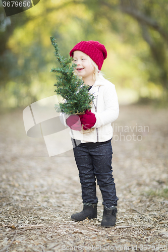 Image of Baby Girl In Red Mittens and Cap Holding Small Christmas Tree