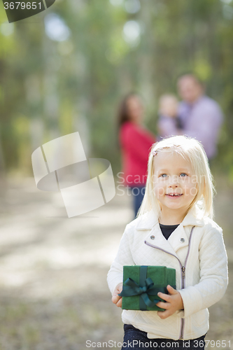 Image of Baby Girl With Christmas Gift Outdoors Parents Behind
