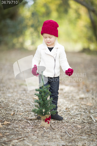 Image of Girl In Red Mittens and Cap Near Small Christmas Tree