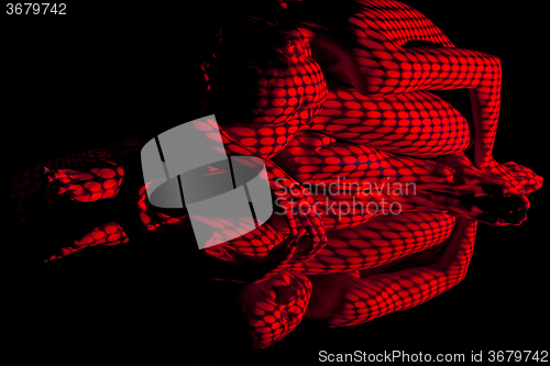 Image of The  body of woman with red pattern and its reflection