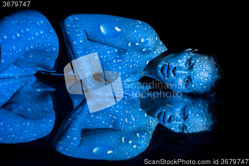 Image of The  body of woman with blue pattern and its reflection