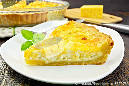 Image of Pie with cheese and leeks in plate on dark board