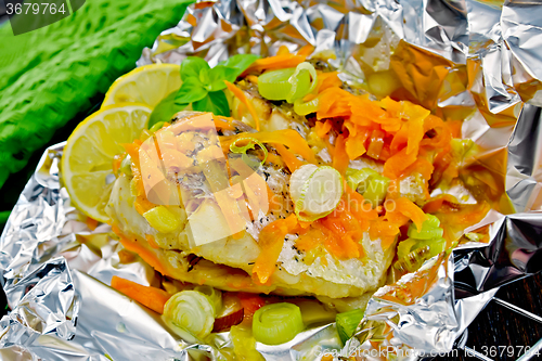 Image of Pike with carrots and leeks in foil on dark board