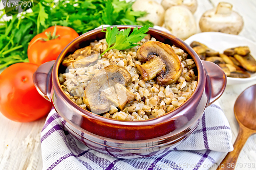 Image of Buckwheat with champignons in clay bowl on towel