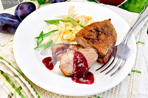 Image of Duck breast with plum sauce and green onions in plate on napkin