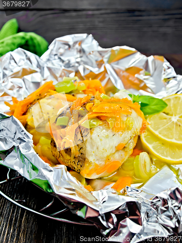 Image of Pike with carrots in foil on dark board