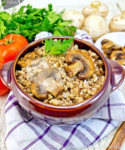 Image of Buckwheat with champignons in clay bowl on light board