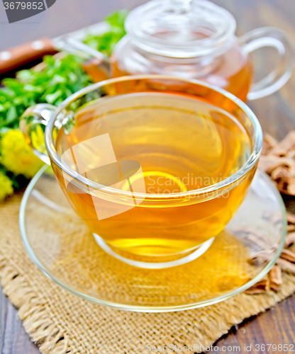 Image of Tea of Rhodiola rosea in glass cup and teapot on sacking