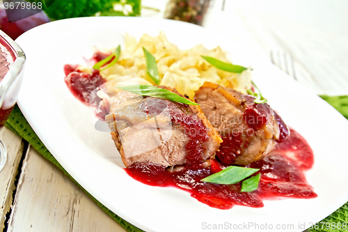 Image of Duck breast with plum sauce and cabbage in plate on green napkin