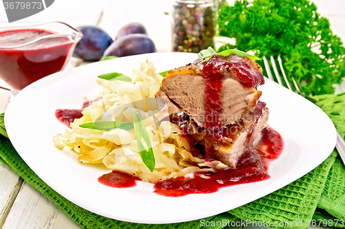 Image of Duck breast whole with plum sauce and cabbage in plate on napkin