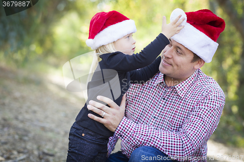 Image of Father and Daughter Having Fun Wearing Santa Hats