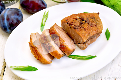 Image of Duck breast with plum sauce and green onions in white plate