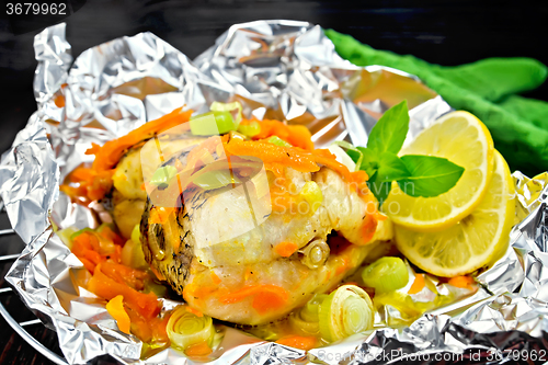 Image of Pike with carrots and onions in foil on dark board