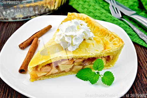 Image of Pie apple with cream and mint in plate on board