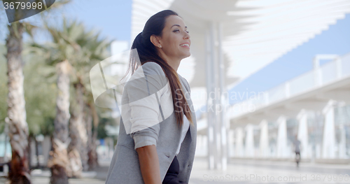 Image of Elegant woman sitting on a bench on a promenade